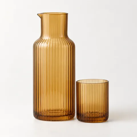 A ribbed amber glass carafe with a tumbler